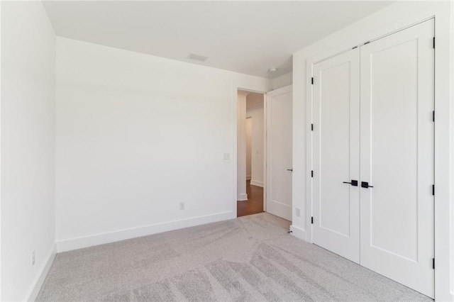 unfurnished bedroom with light colored carpet and a closet