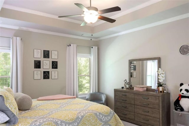 bedroom with ceiling fan, a raised ceiling, ornamental molding, and multiple windows