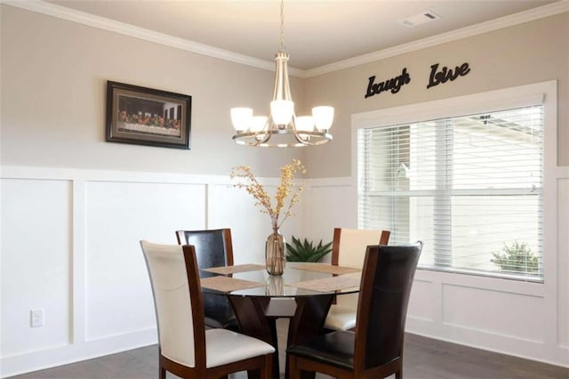 dining area featuring dark hardwood / wood-style flooring, ornamental molding, and an inviting chandelier