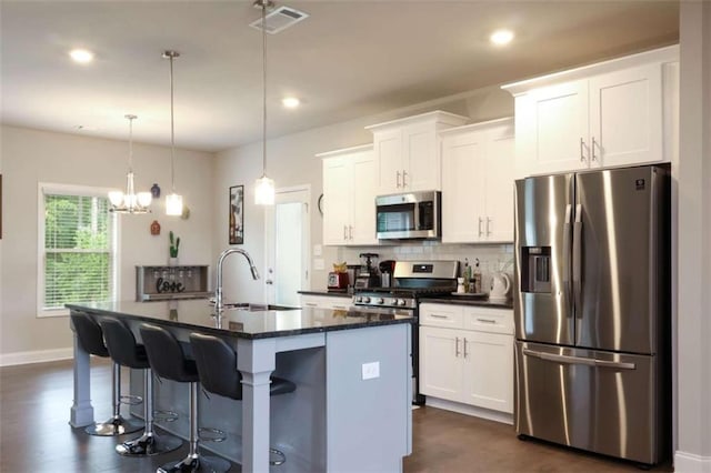 kitchen with stainless steel appliances, sink, a center island with sink, white cabinets, and dark hardwood / wood-style floors