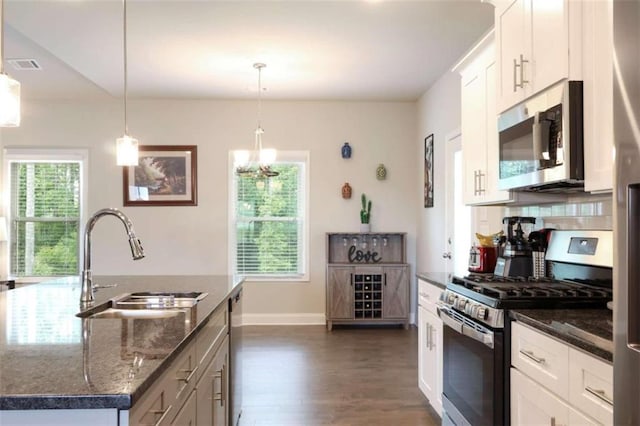 kitchen featuring white cabinetry, sink, an island with sink, pendant lighting, and appliances with stainless steel finishes