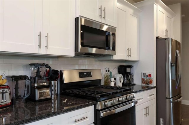 kitchen with dark stone countertops, decorative backsplash, white cabinets, and appliances with stainless steel finishes