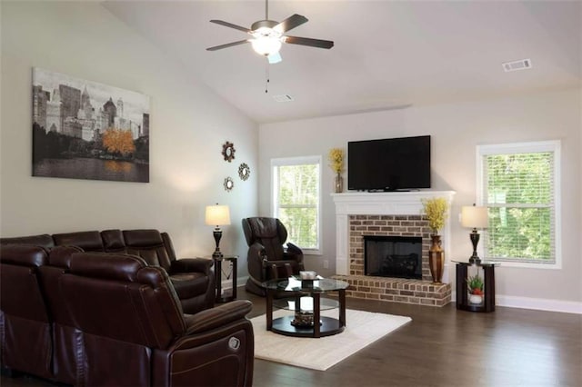 living room featuring ceiling fan, dark hardwood / wood-style flooring, vaulted ceiling, and a brick fireplace