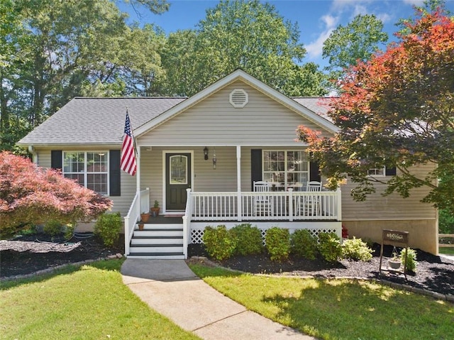 view of front of home with covered porch, a front lawn, and roof with shingles