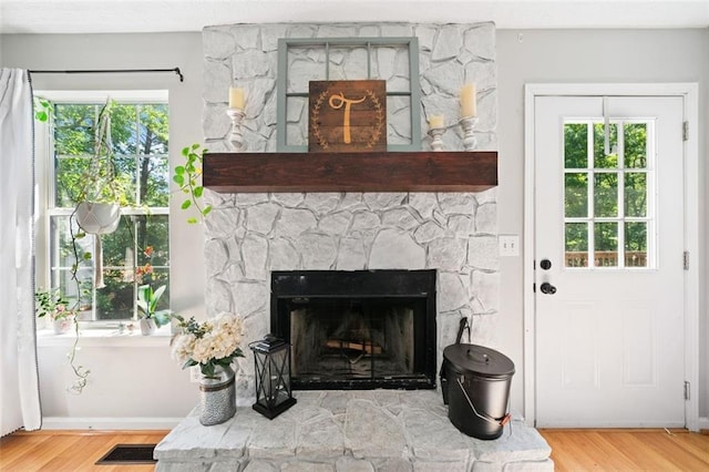 detailed view of a fireplace, wood finished floors, and baseboards