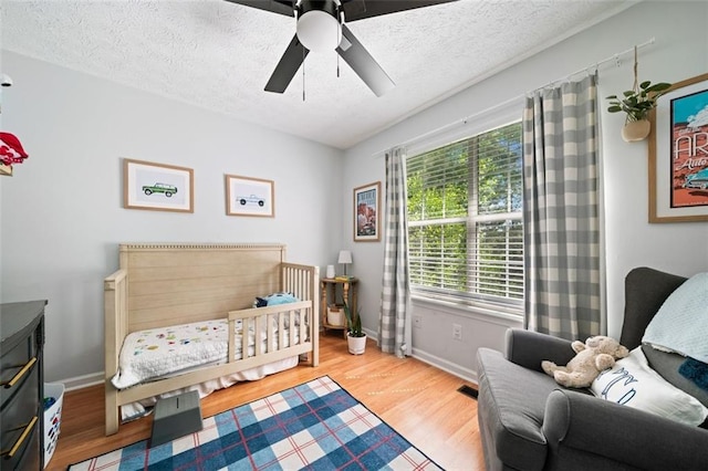 bedroom featuring wood finished floors, a textured ceiling, baseboards, and ceiling fan