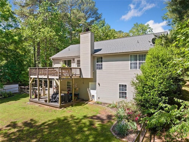 rear view of house with a deck, a lawn, and a chimney