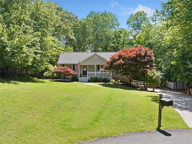 view of front facade featuring a porch, a storage shed, a front lawn, and an outdoor structure