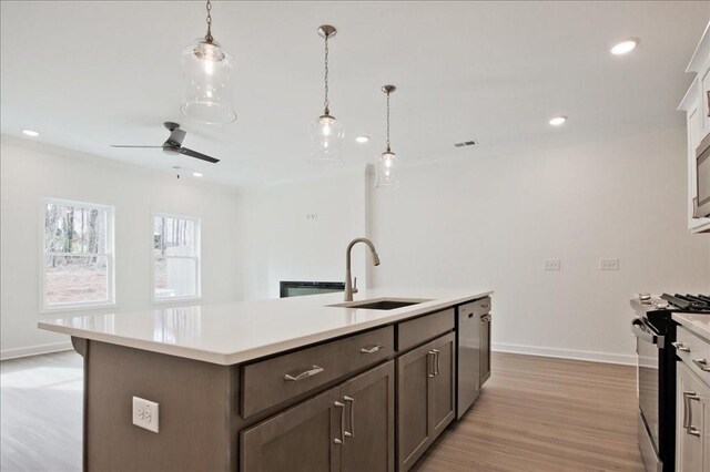 kitchen featuring black gas range, dishwasher, light countertops, light wood-style floors, and a sink