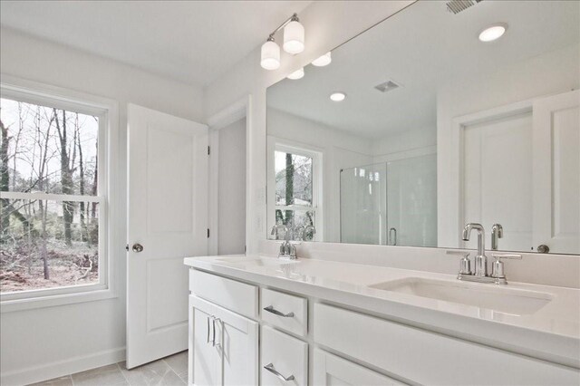 full bath featuring a sink, baseboards, a stall shower, and double vanity