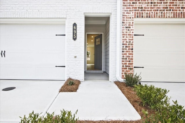 view of exterior entry with a garage and brick siding