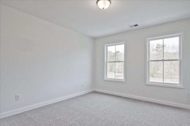 unfurnished room with light colored carpet, visible vents, and baseboards