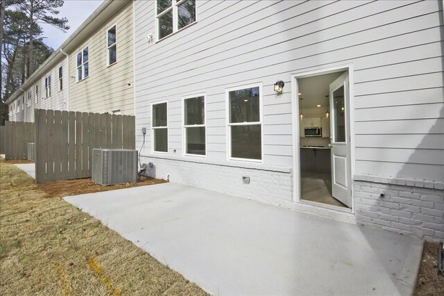 view of patio with central air condition unit and fence