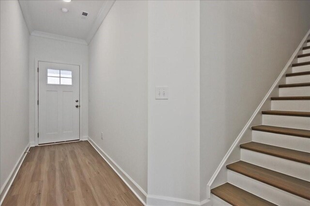 doorway with baseboards, wood finished floors, stairs, and ornamental molding