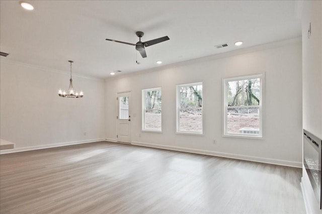 empty room featuring visible vents, baseboards, wood finished floors, and crown molding