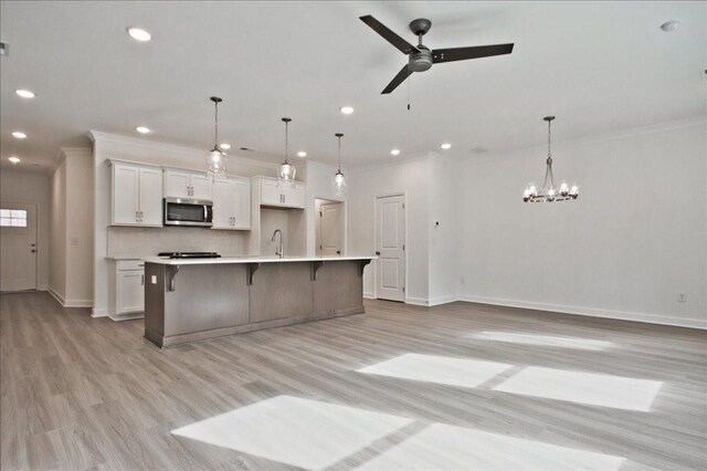 kitchen with a breakfast bar area, stainless steel microwave, white cabinets, and crown molding