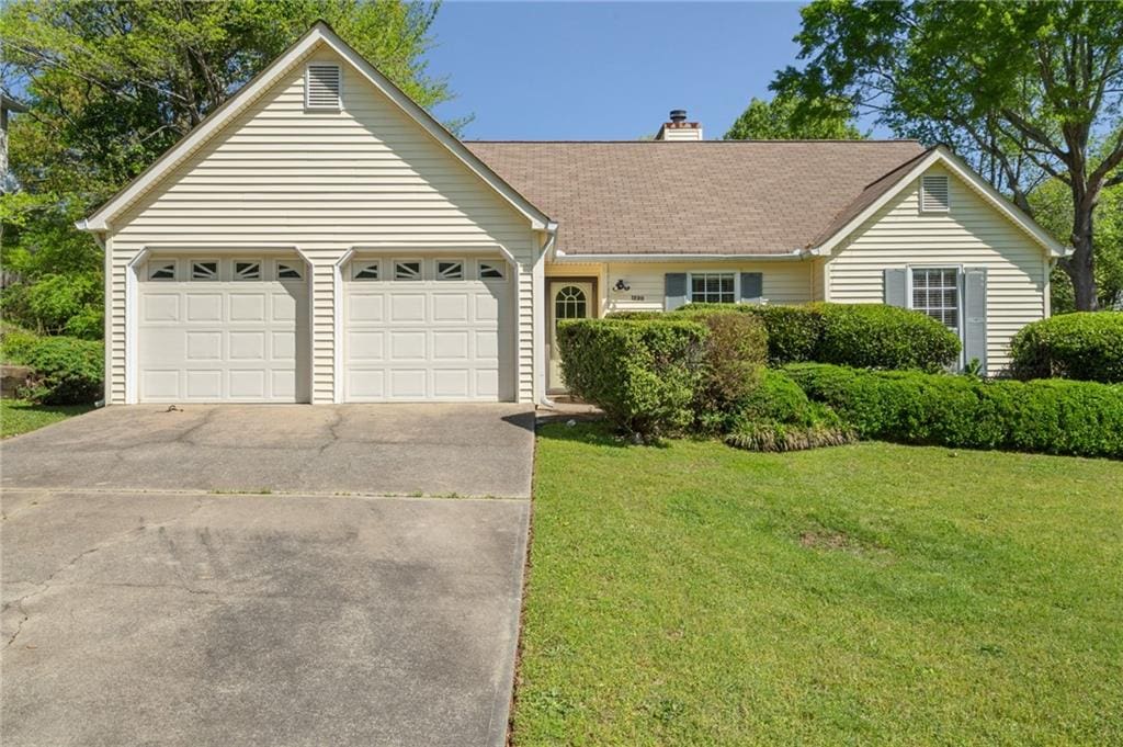 ranch-style house with an attached garage, a chimney, concrete driveway, and a front lawn