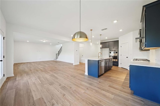 kitchen featuring pendant lighting, open floor plan, light countertops, and a center island with sink