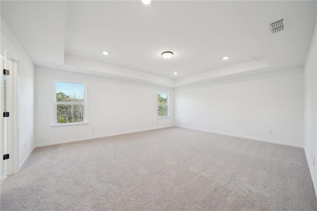 spare room featuring baseboards, visible vents, and a raised ceiling