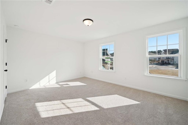 spare room with baseboards, visible vents, and light colored carpet