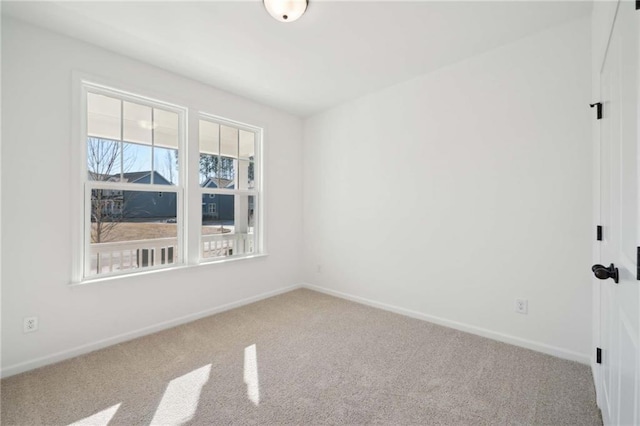 carpeted spare room featuring baseboards