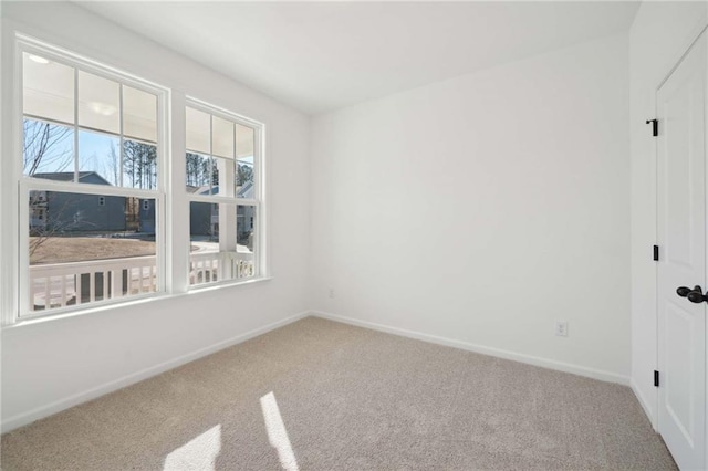 carpeted spare room featuring baseboards