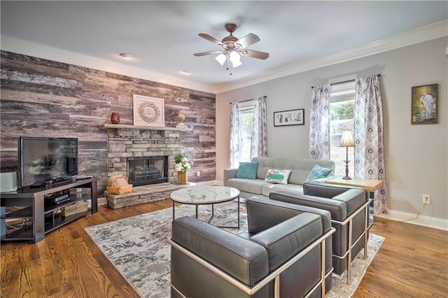 living room featuring crown molding, a wealth of natural light, a stone fireplace, and hardwood / wood-style floors