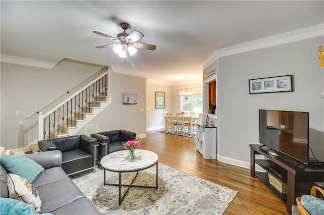 living room with ceiling fan with notable chandelier, ornamental molding, and hardwood / wood-style flooring