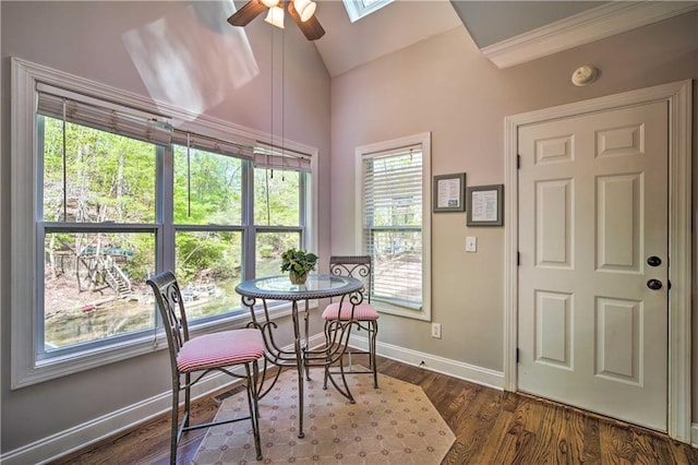 dining space featuring ceiling fan, dark hardwood / wood-style floors, lofted ceiling with skylight, and ornamental molding