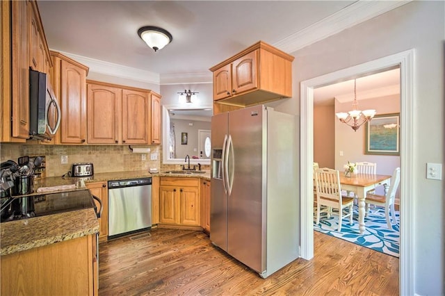 kitchen featuring decorative light fixtures, hardwood / wood-style floors, sink, ornamental molding, and stainless steel appliances