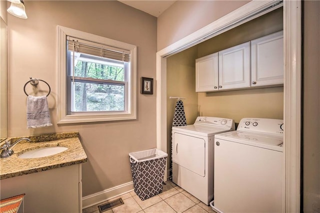 washroom featuring cabinets, light tile patterned flooring, washing machine and clothes dryer, and sink