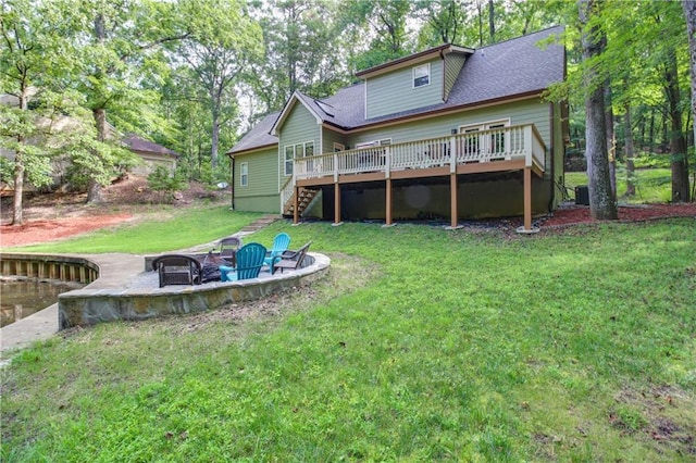 rear view of property with a wooden deck, cooling unit, a fire pit, and a lawn