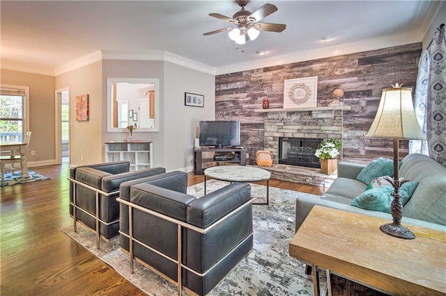 living room featuring ceiling fan, crown molding, a fireplace, and hardwood / wood-style floors