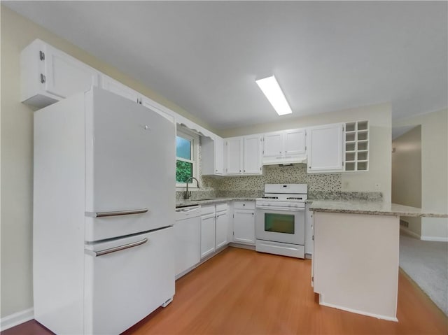 kitchen featuring sink, kitchen peninsula, white appliances, white cabinets, and light wood-type flooring