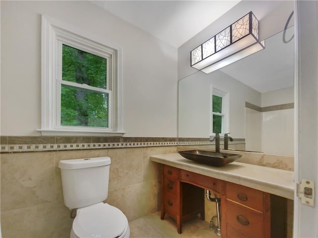 bathroom with vanity, toilet, and tile walls