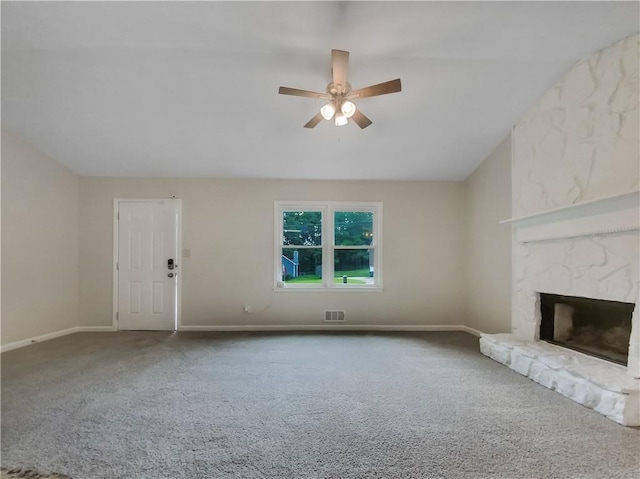 unfurnished living room with a stone fireplace, ceiling fan, carpet floors, and lofted ceiling