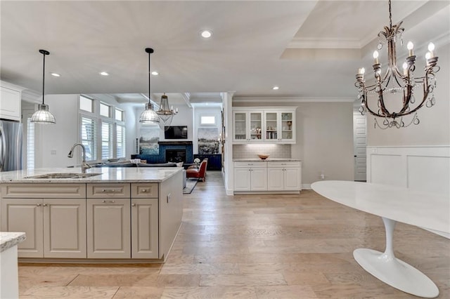 kitchen with crown molding, a sink, white cabinets, and a fireplace