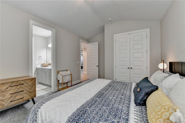 bedroom with ensuite bathroom, lofted ceiling, and a closet