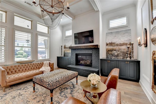 living area with crown molding, light wood-style flooring, a chandelier, and visible vents