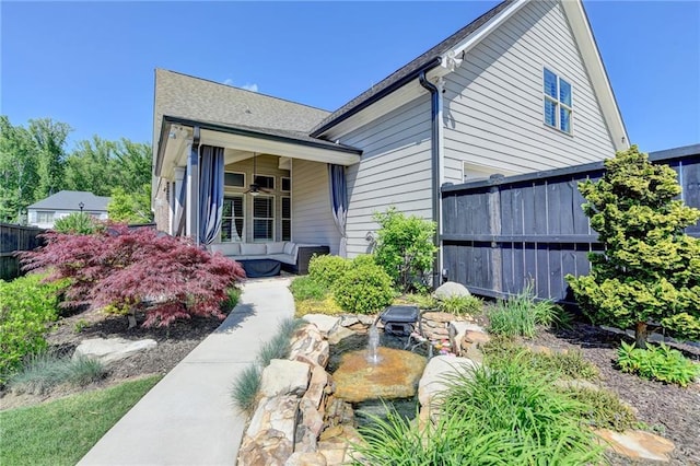 view of home's exterior with fence and a ceiling fan