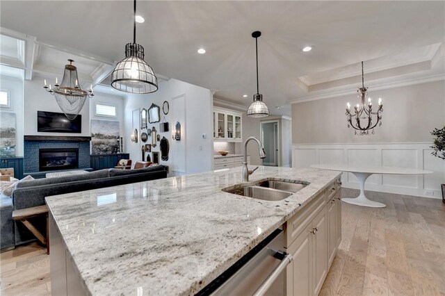kitchen with a sink, ornamental molding, light wood-style floors, and a notable chandelier