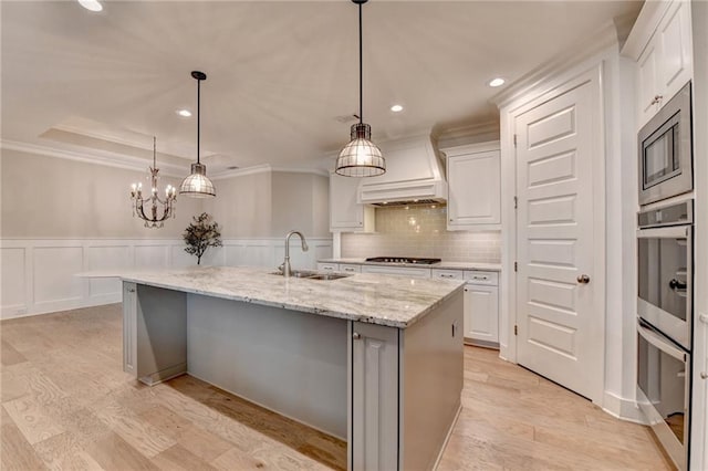 kitchen with crown molding, white cabinets, appliances with stainless steel finishes, and a sink