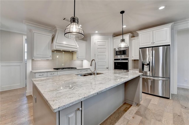 kitchen with white cabinets, appliances with stainless steel finishes, a sink, light wood-style flooring, and tasteful backsplash