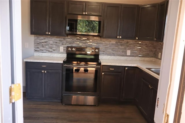 kitchen with dark hardwood / wood-style floors, dark brown cabinetry, appliances with stainless steel finishes, and tasteful backsplash