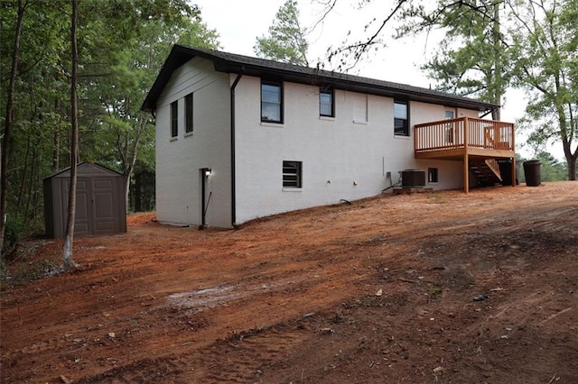 back of property featuring a wooden deck, a storage unit, and central air condition unit