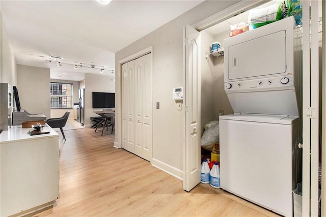 laundry room featuring laundry area, stacked washer and clothes dryer, and light wood-type flooring