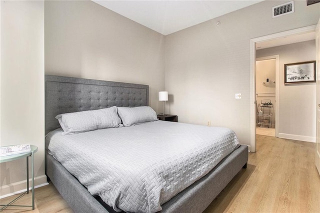 bedroom with baseboards, visible vents, and light wood finished floors