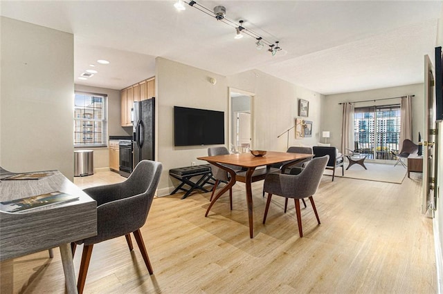 dining space with baseboards, a healthy amount of sunlight, and light wood-style flooring