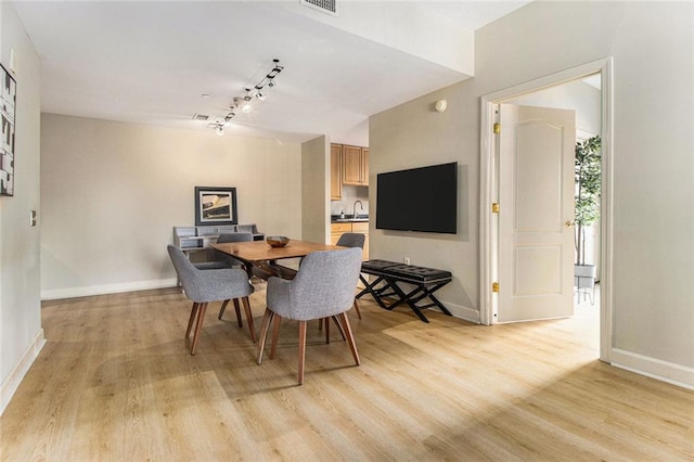 dining area with baseboards, visible vents, light wood-style flooring, and rail lighting