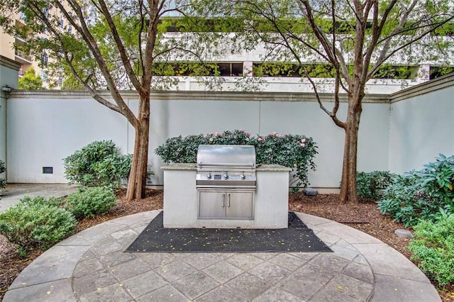 view of patio featuring exterior kitchen, fence, and a grill